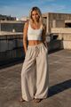 Sommerliches Stadtoutfit: Off-White geripptes Baumwolltop kombiniert mit einer weit geschnittenen beigefarbenen Leinenhose.