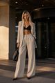 Moderner Leinenanzug: Leinenanzug in hellem Beige mit locker geschnittenem Blazer und weit geschnittener Hose, kombiniert mit einem schwarzen Bralette-Top.