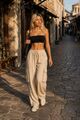 Urbanes Leinenensemble: Schwarzes Bandeau-Top kombiniert mit einer weit geschnittenen beigefarbenen Leinenhose mit aufgesetzten Seitentaschen.